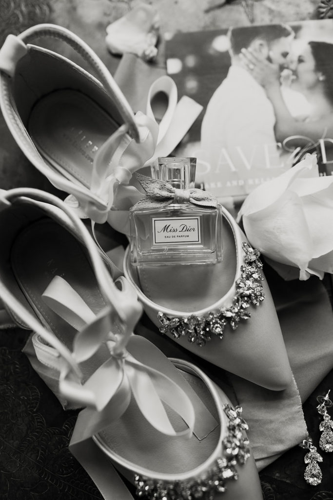 Black and white wedding detail photo of shoesand perfume